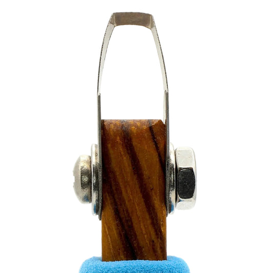 Wooden reel with metal accents on a blue cushion against a white background