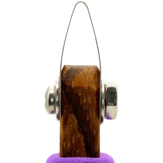 Wooden object with metallic components on a purple stand against a white background